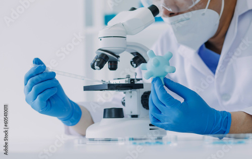 medical or scientific researcher researching and experimenting Multi-colored solution, vial and microscope In the laboratory or in the laboratory by wearing blue gloves and white clothing completely.