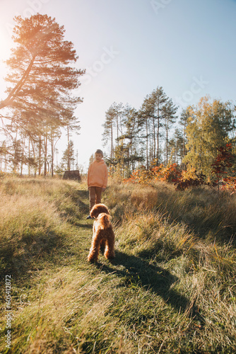 A boy with a small brown dog walks in a park. Leisure with a pet in nature. Front view