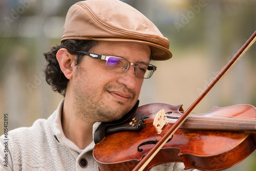 man composing music in the park playing a violin