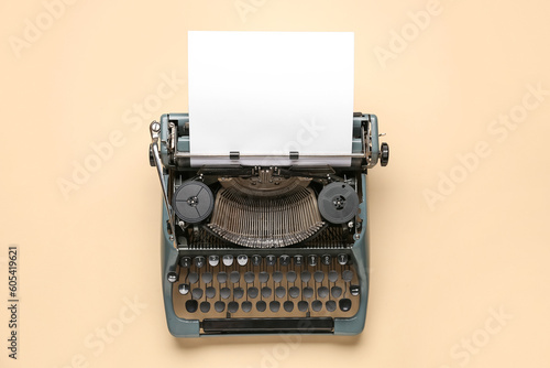 Vintage typewriter with blank paper sheet on beige background