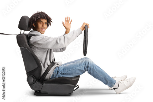 African american young man in a driver seat holding a steering and waving