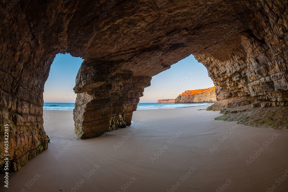 Large cave in the coastal cliffs at a beach (Praia do Beliche) of the Algarve at sunrise, Portugal
