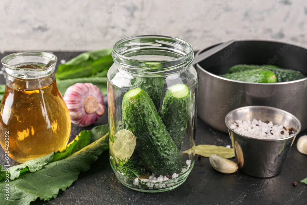Jar with fresh cucumbers and ingredients for preservation on table Jar with fresh cucumbers and ingredients for preservation on table