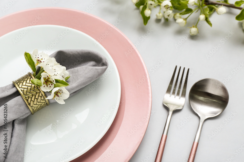 Beautiful table setting with blooming tree branches on grey background Beautiful table setting with blooming tree branches on grey background