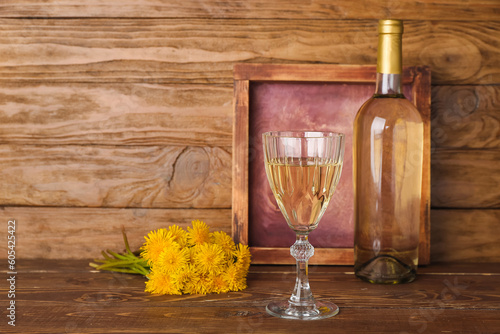 Bottle and glass of dandelion wine on wooden table