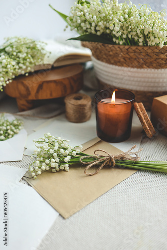 Festive concept, lily of the valley bouquet, gift box , burning candle and letter