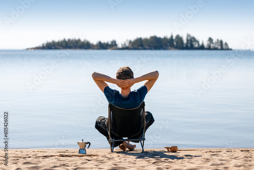 A man is resting in a camping chair on the seashore. photo