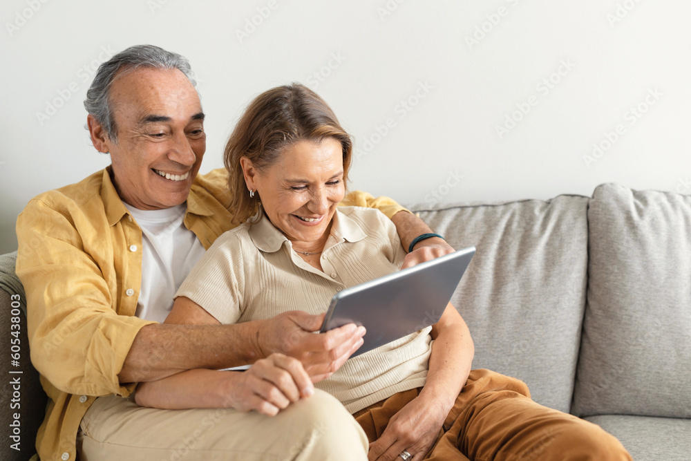 Retirement and internet fun concept. Excited senior spouses using digital tablet, websurfing or watching film online Retirement and internet fun concept. Excited senior spouses using digital tablet, websurfing or watching film online