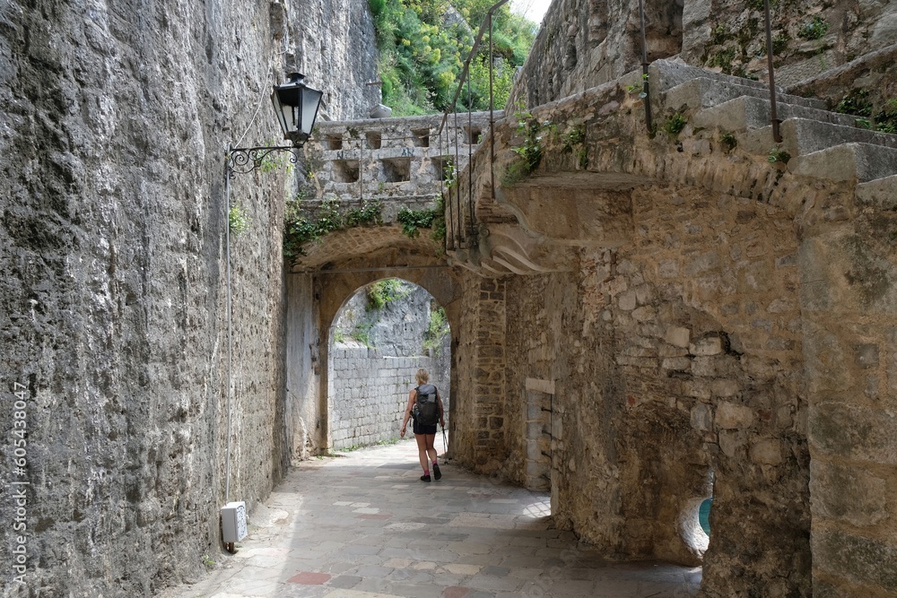 Fortress wall in Kotor. Kotor is a beautiful historic city on the Unesco list. Silhouettes of walking woman under arch.