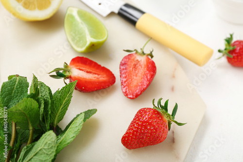 Fototapeta Naklejka Na Ścianę i Meble -  Board with ripe strawberry, lime, lemon and mint on light background, closeup