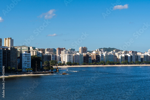 View of the edge of Praia de Icaraí, a neighborhood in Niterói, Rio de Janeiro, Brazil. Buildings and houses in front of the beach, surrounded by hills and nature. Bathed by Guanabara Bay. Sunny day