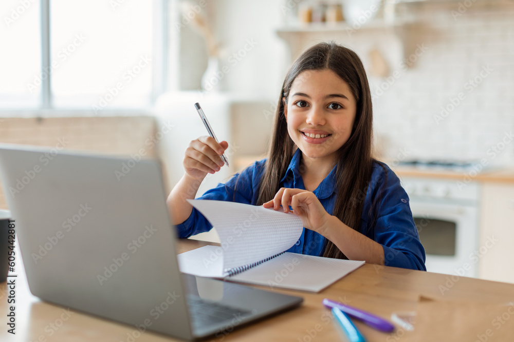 Schoolgirl Engaging in Distance Learning Via Laptop Taking Notes Indoors Schoolgirl Engaging in Distance Learning Via Laptop Taking Notes Indoors