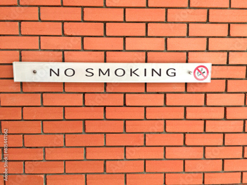 No smoking sign on an orange brick wall.