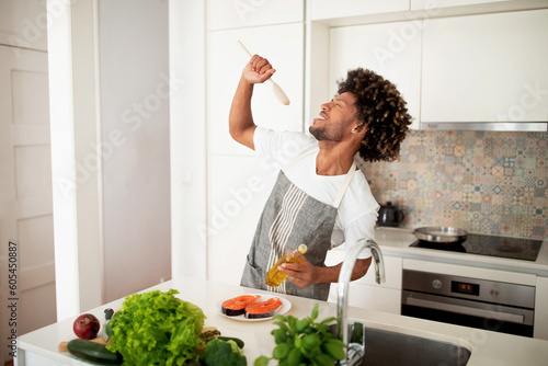 Foto Black Cook Man Singing With Spoon In Hand In Kitchen