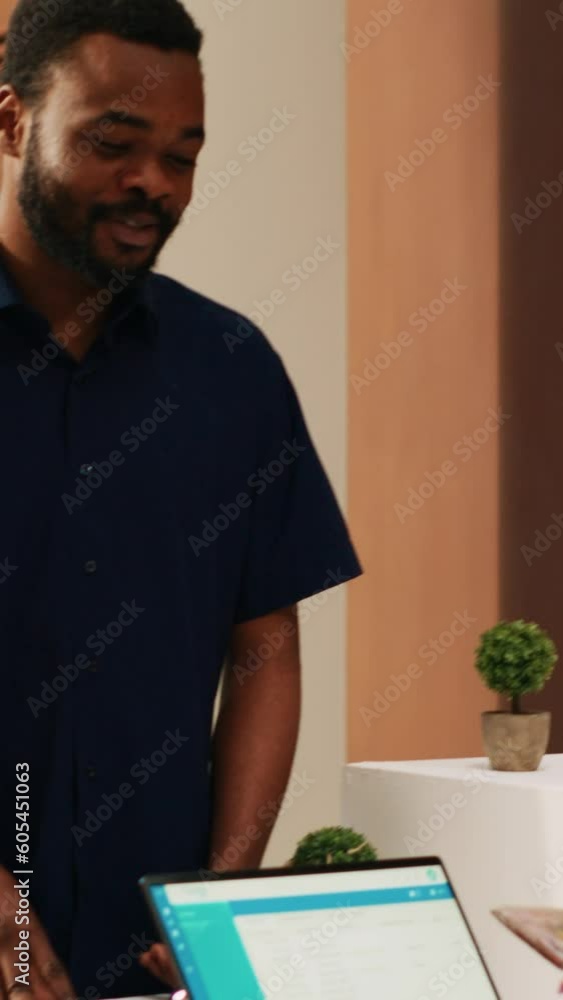 Vertical video Receptionist looking at passports to register tourists at exotic seaside resort, talking to couple on honeymoon trip. Hotel guests doing check in procedure with front desk staff Vertical video Receptionist looking at passports to register tourists at exotic seaside resort, talking to couple on honeymoon trip. Hotel guests doing check in procedure with front desk staff