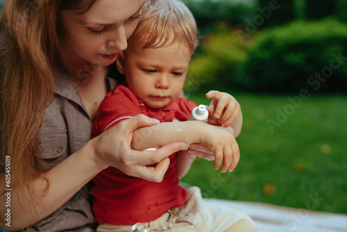 Cuadro en lienzo Mother puts cream on baby's hand in summer