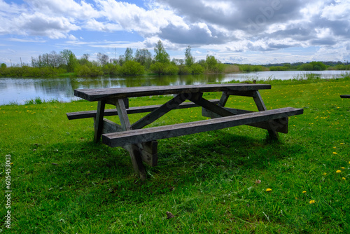 A wooden bench with a table for a picnic by the lake. Nice place to relax