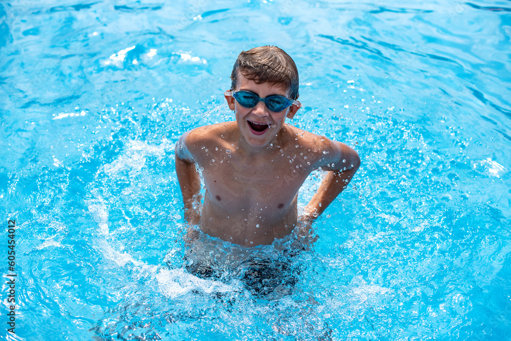 Underwater teen boy in the swimming pool with goggles in sunny day. Children Summer Fun. Kids water sport activity on summer holiday.