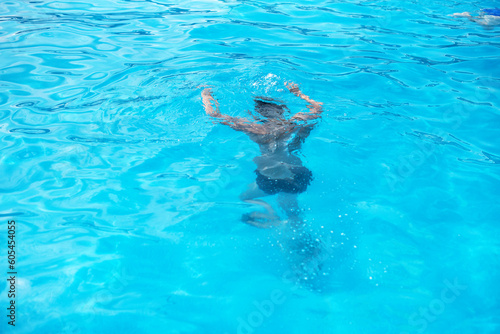 Underwater teen boy in the swimming pool with goggles in sunny day. Children Summer Fun. Kids water sport activity on summer holiday.