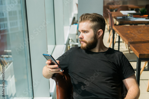 Fashionable young bearded guy wears stylish clothes and trendy hairstyle and happy to exchange messages with friends and uses free internet connection on electronic modern gadget copy space - social © satura_