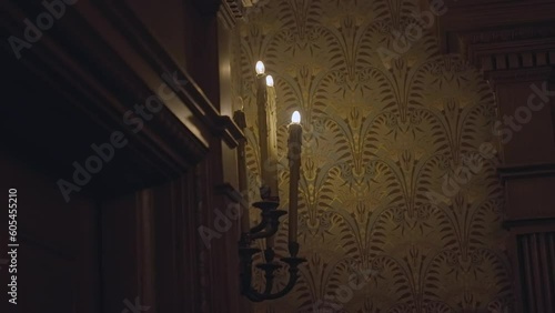 This video shows ominous sconce candles flickering on the wall of an old victorian mansion.