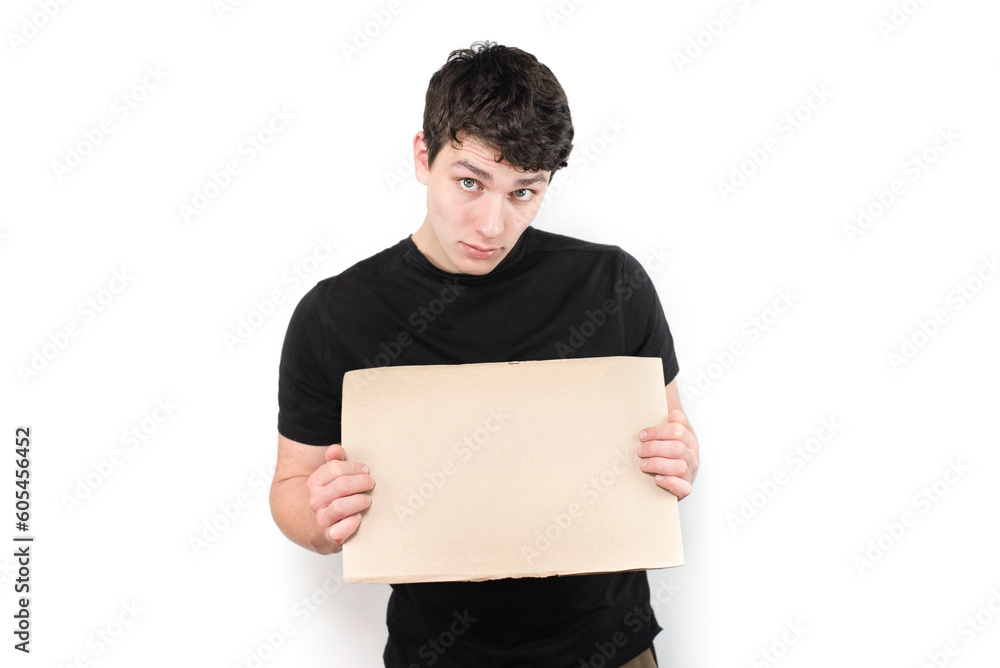 A young guy with emotions of wonder and surprise holds a cardboard sign in his hands for inscriptions. A sign in hands of a handsome guy on a light background A young guy with emotions of wonder and surprise holds a cardboard sign in his hands for inscriptions. A sign in hands of a handsome guy on a light background