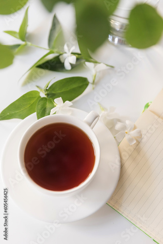 Cup of tea with notepad and white flowers.