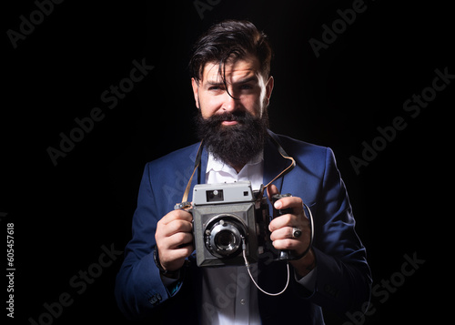 Bearded old man photographer with a large old professional camera. Portrait of man photographer with vintage retro old film camera isolated on a black background. Retro photographer.