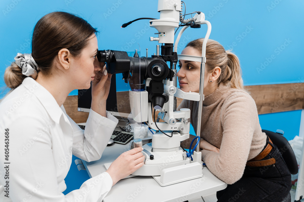 Ophthalmologist with slit lamp examines eyes and cornea of woman. Ophthalmologist illuminates eye of patient with light from slit lamp to diagnose the eyes and cornea. Ophthalmologist with slit lamp examines eyes and cornea of woman. Ophthalmologist illuminates eye of patient with light from slit lamp to diagnose the eyes and cornea.