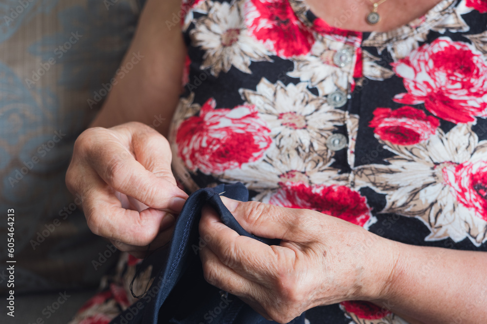Hands of an unrecognizable old woman sewing and ripping with a sewing