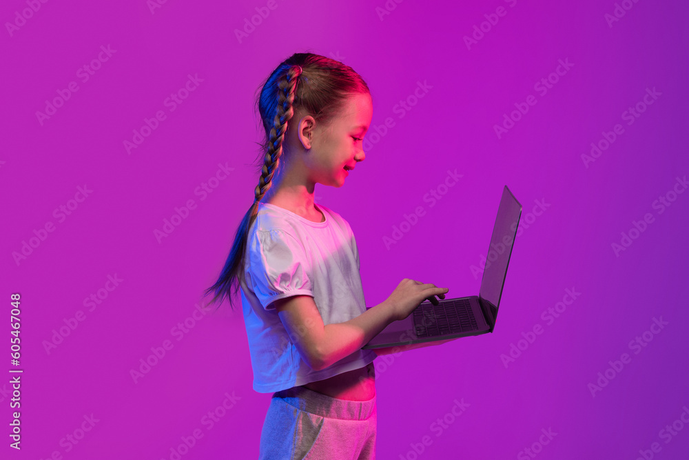 School aged little girl typing on laptop keyboard School aged little girl typing on laptop keyboard