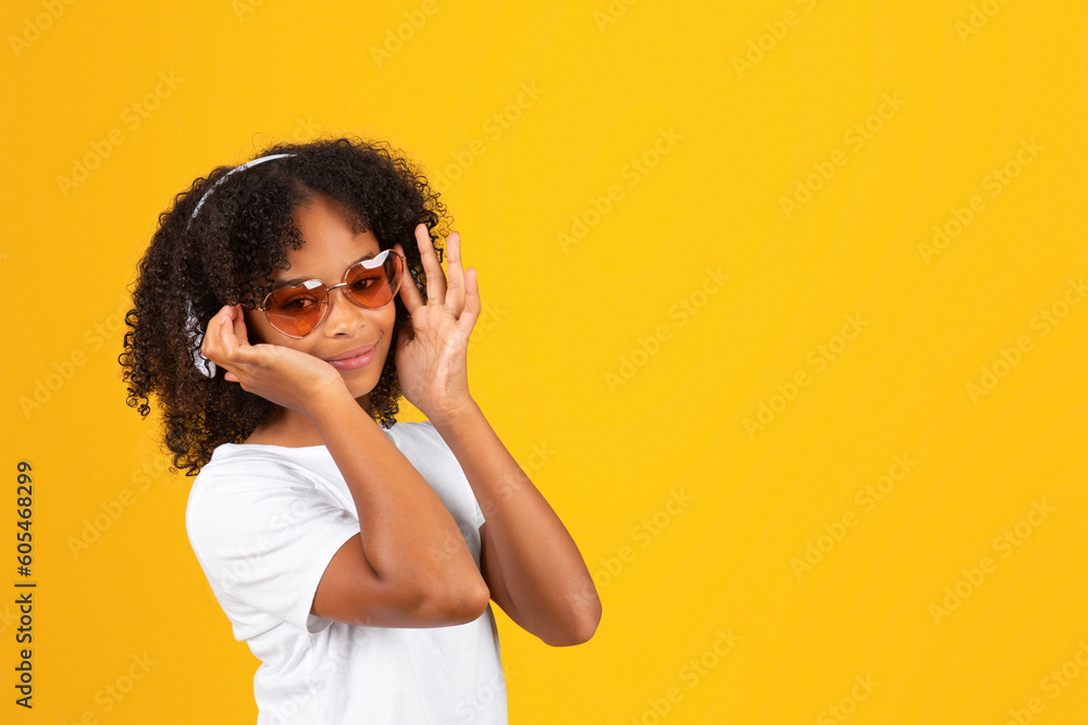 Cheerful curly teen african american girl in white t-shirt, sunglasses and wireless headphones listen music Cheerful curly teen african american girl in white t-shirt, sunglasses and wireless headphones listen music
