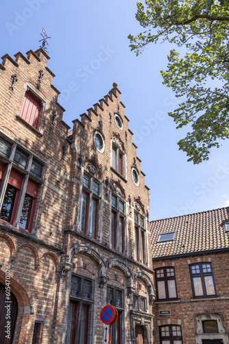 Architecture of medieval brick houses in Bruges in Belgium lined up against a blue sky.