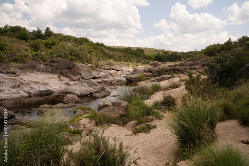 Panorama view of the river flowing across the rocky hill and forest.