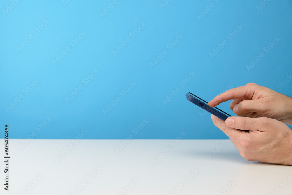 main d'un homme qui tient un smartphone sur fond bleu de studio pour publicité main d'un homme qui tient un smartphone sur fond bleu de studio pour publicité