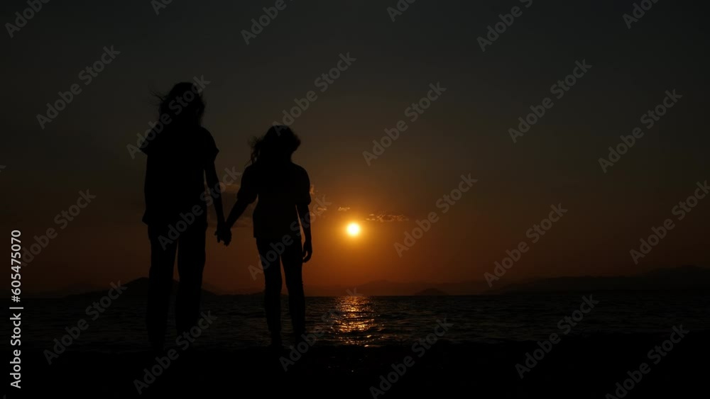 Sisters at sunset. Silhouette of two sisters at sunset on a windy beach. Sisters at sunset. Silhouette of two sisters at sunset on a windy beach.