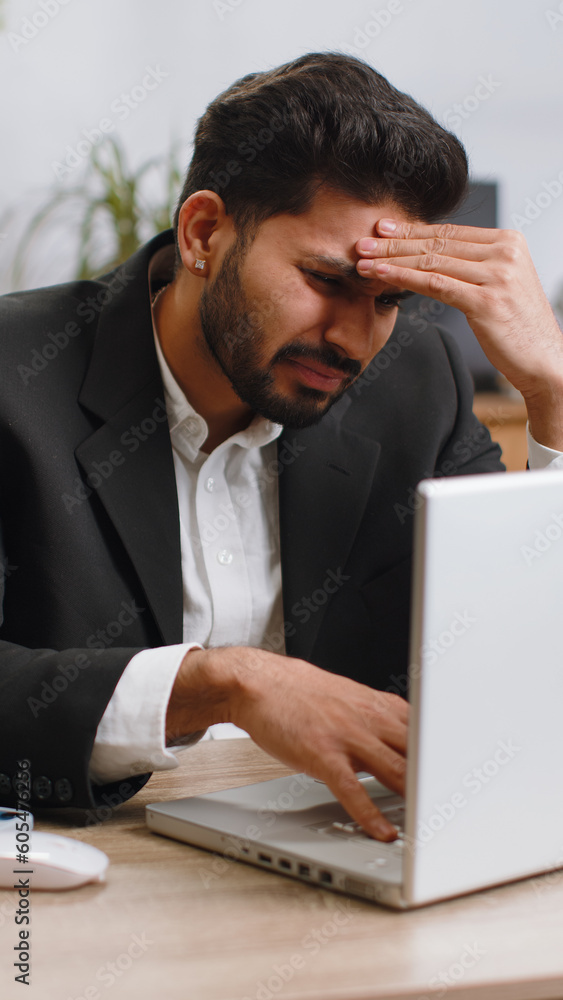 Indian businessman programmer software developer working on laptop loses becoming surprised by bad news results, fortune loss fail at home office. Deadline, bankruptcy. Freelancer man. Vertical shot Indian businessman programmer software developer working on laptop loses becoming surprised by bad news results, fortune loss fail at home office. Deadline, bankruptcy. Freelancer man. Vertical shot