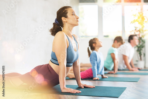 Family with son and daughter practicing yoga in virabhadrasana pose in the gym
