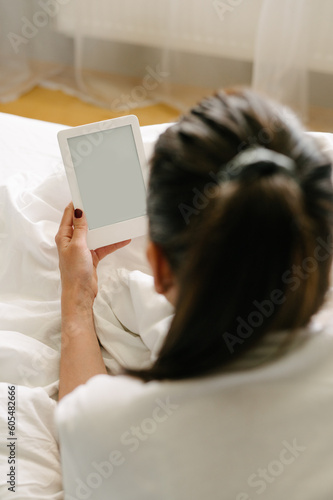 Woman using tablet on bed during weekend