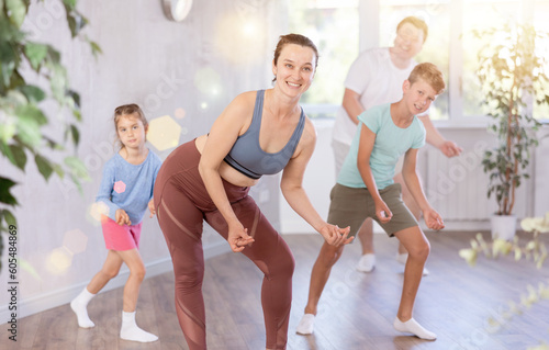 Active, positive family has fun at home. Parents with young daughter and schoolboy son are taught to move to boogie-woogie