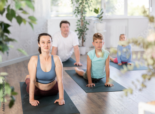 Fototapeta Naklejka Na Ścianę i Meble -  Family with two children doing yoga on mats in fitness studio..