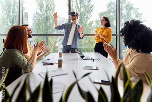 Young man wearing VR goggles, playing virtual reality online games during team building training