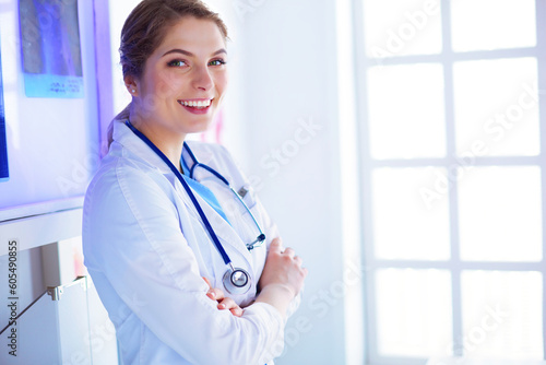 Young woman medic in white uniform standing in clinic's office