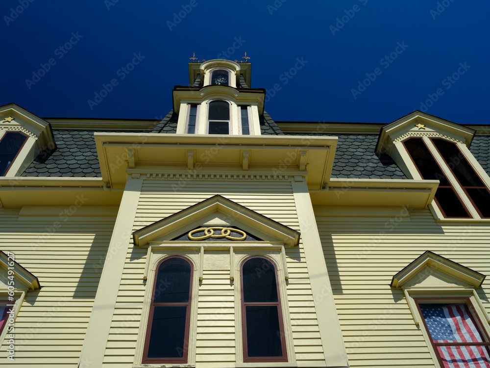 Looking up at an old Colonial Yellow building against a perfect blue sky on Vinalhaven Island Maine