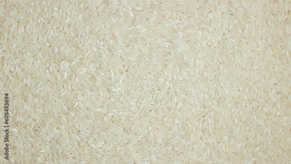 Dry Uncooked White Rice Background Slowly Rotating Left - Top View. Scattered Raw Long Grain Rice. Asian Cuisine and Culture. Healthy Eating Ingredients. Diet Food Dry Uncooked White Rice Background Slowly Rotating Left - Top View. Scattered Raw Long Grain Rice. Asian Cuisine and Culture. Healthy Eating Ingredients. Diet Food