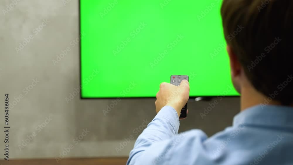 Man sitting on the couch, choosing channel and watching tv. Green screen concept Man sitting on the couch, choosing channel and watching tv. Green screen concept