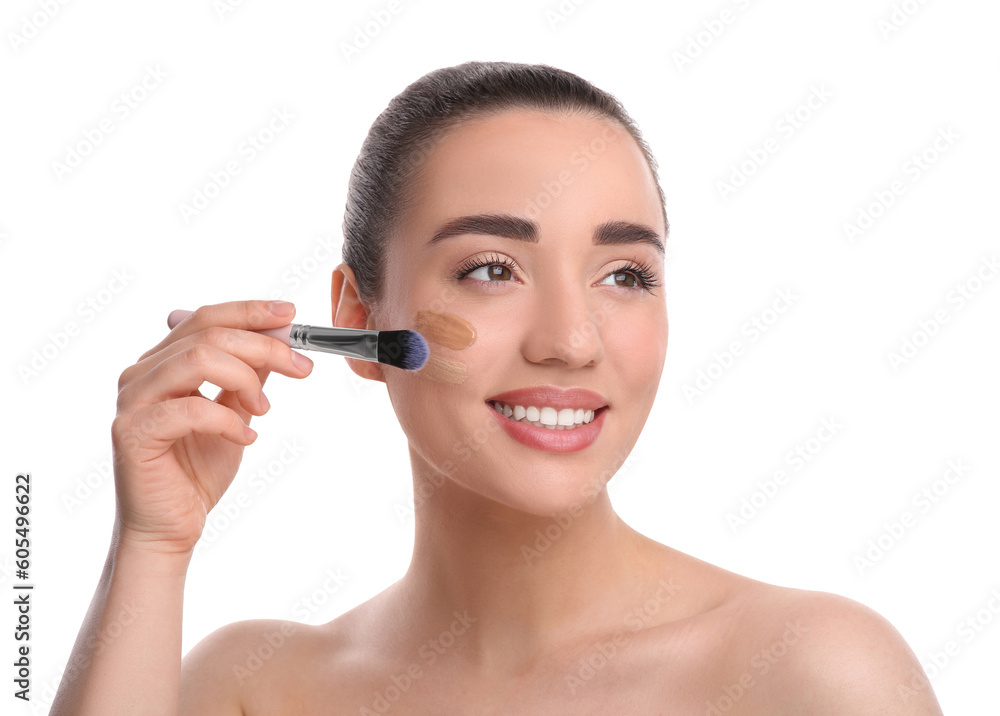 Woman applying foundation on face with brush against white background Woman applying foundation on face with brush against white background