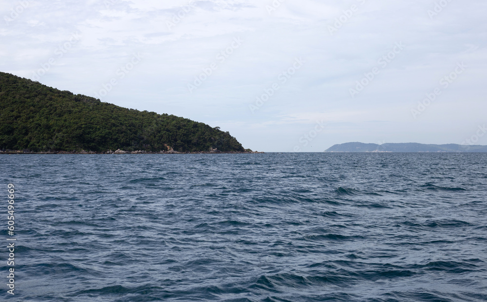 Island in the blue sea. Blue ocean water surface texture. Summer background. Island in the blue sea. Blue ocean water surface texture. Summer background.