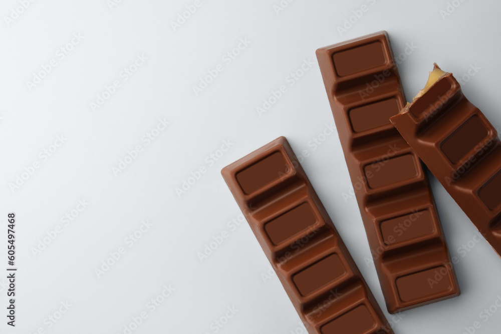 Delicious chocolate bars on light blue background, flat lay. Space for text Delicious chocolate bars on light blue background, flat lay. Space for text