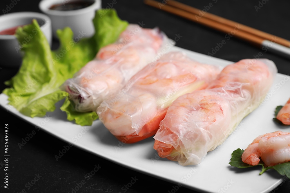 Delicious spring rolls with shrimps wrapped in rice paper served on black table, closeup Delicious spring rolls with shrimps wrapped in rice paper served on black table, closeup